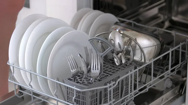 Offene Spülmaschine mit sauberen Tellern und Besteck verschließen. — Stockfoto