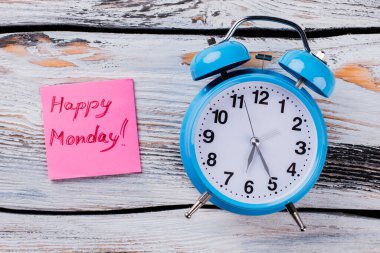 Çalar saat ve kağıt etiketi Mutlu Pazartesi sloganı.