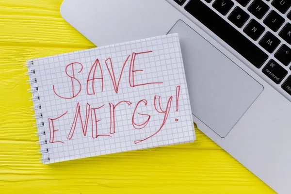 Notepad with save energy slogan and laptop keyboard.
