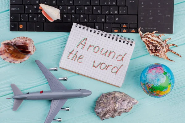 飛行機、地球、貝殻やノートパッドとフラットレイ旅行組成物青い机の上. — ストック写真