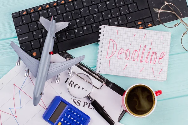 Κόκκινη προθεσμία λέξεις στο σημειωματάριο με προμήθειες γραφείου και παιχνίδι αεροπλάνο. — Φωτογραφία Αρχείου