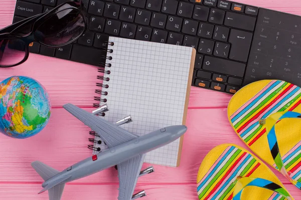 Κενό σημειωματάριο με γυναικεία αξεσουάρ ταξιδιώτη γυαλιά πορτοφόλι και σαγιονάρες σε ροζ φόντο τραπέζι. — Φωτογραφία Αρχείου