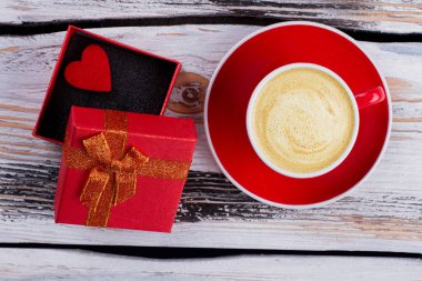 Bir fincan köpüklü kahve ve açık hediye kutusu..