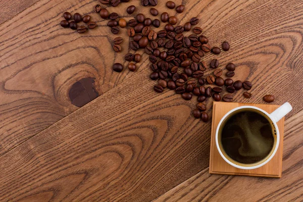 Topview taza de café y granos de café dispersos en madera . —  Fotos de Stock