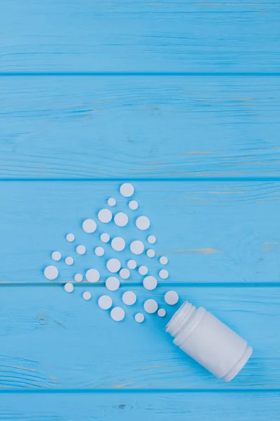 White bottle and white meds on blue wooden table.