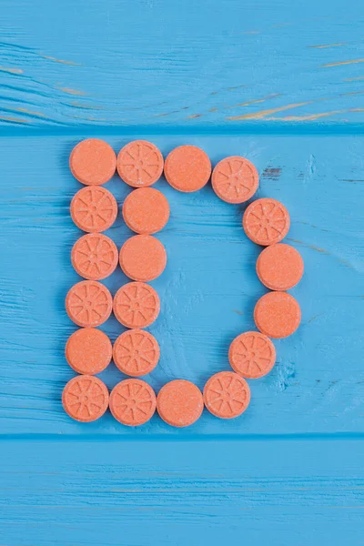 Round orange pills in a shape of letter d. — Stock Photo, Image