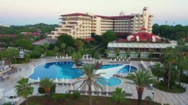 Yüzme havuzları ve palmiye ağaçları olan otel manzarası.
