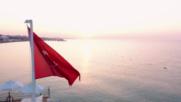 Bandera turca ondea en el viento contra el mar al atardecer . — Vídeo de stock