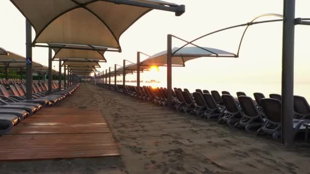 Beach loungers and umbrellas on an empty beach in the evening. — Stock Video