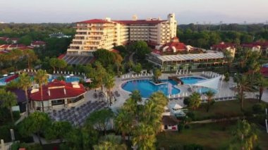 Havuzu ve palmiyeleri olan güzel bir otel manzarası.