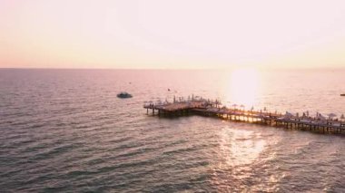 Gün batımında deniz kıyısındaki ahşap iskelenin havadan görünüşü.