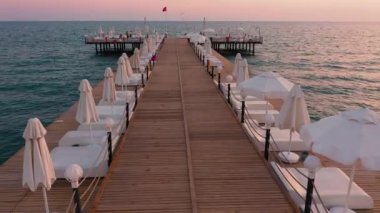 Gün batımında denizdeki uzun tahta iskele manzarası.