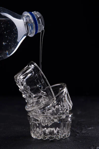 Wasser strömt aus Plastikflasche in Glasschüsseln. — Stockfoto