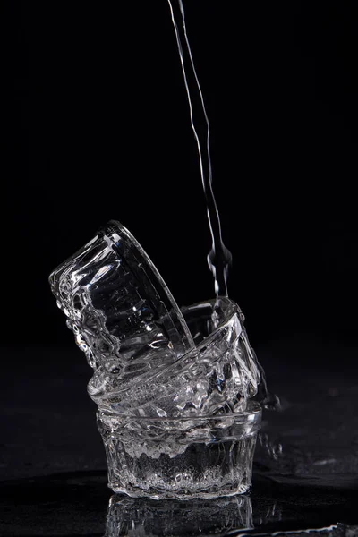 El agua que fluye está llenando la pila de tres tazas de vidrio . —  Fotos de Stock