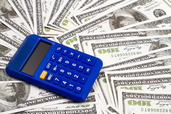 Calcolatrice blu su un mucchio di dollari. — Foto Stock