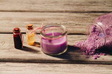 Ahşap arka planda pembe mum ve spa şeyleri.