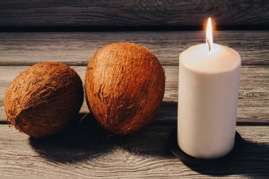 Hindistan cevizlerinin ve yanan mumların kaplıca bileşimi ahşap arka planda.