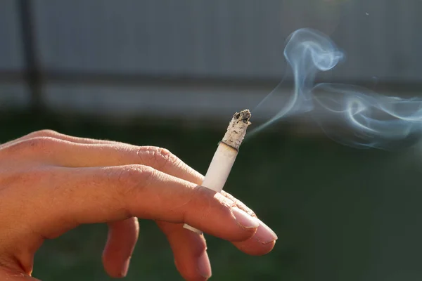 Mão de adolescente segurando cigarro ardente . — Fotografia de Stock