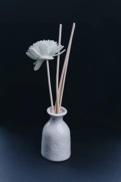 O vaso branco com flores de spa artificiais e varas de aroma de madeira no fundo escuro . — Fotografia de Stock