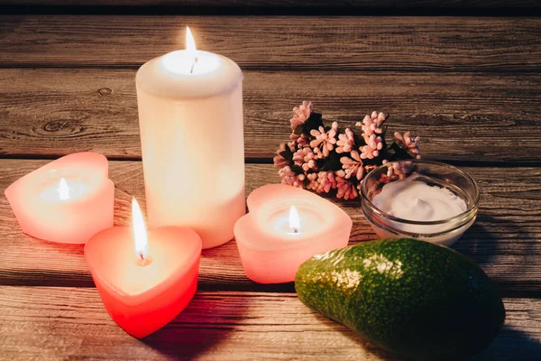 Spa samenstelling van kaarsen handdoeken, bloemen en avocado op houten tafel. — Stockfoto