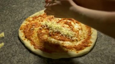 Şef pizzaya peynir koyuyor..