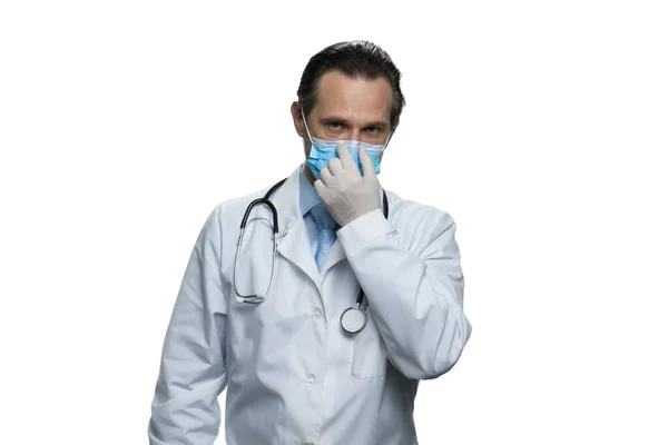 Reifer amerikanischer Arzt mit Stethoskop, das seine Atemschutzmaske berührt. — Stockfoto