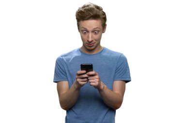 Şaşırmış genç adam akıllı telefonuna bakıyor ve daktilo yazıyor..