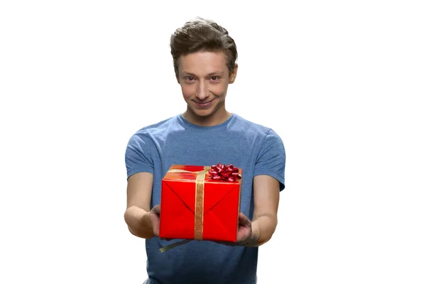 Ritratto di ragazzo caucasico sorridente che mostra scatola regalo rossa con entrambe le mani. — Foto Stock