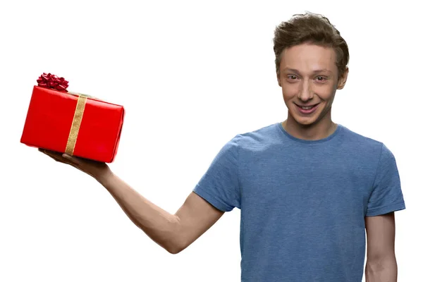 Ragazzo adolescente è in possesso di scatola regalo rosso con sulla sua mano destra. — Foto Stock