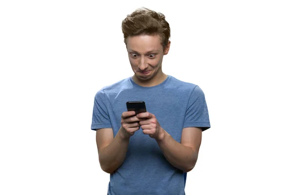 Adolescente sorprendido con los ojos ampliamente abiertos está mirando a la pantalla de su teléfono inteligente y escribiendo . — Foto de Stock