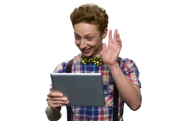 Teenage boy is waving hand saying hello to someone online using his tablet pc. — Stock fotografie