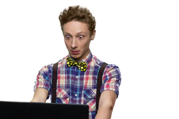 Portrait of teenage guy looking at pc screen with his eyes widely opened. — Stock Photo, Image