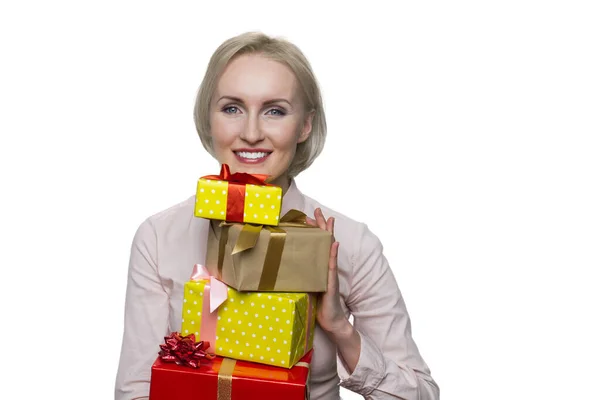 Mulher loira bonita em blusa branca segurando um monte de caixas de presente no fundo branco . — Fotografia de Stock