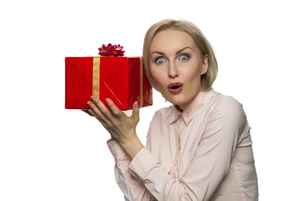 Mulher surpreendida colocando sua orelha para o presente em papel vermelho . — Fotografia de Stock