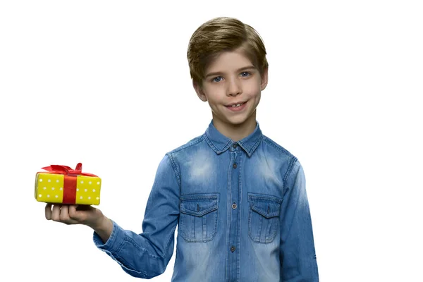 Щасливий хлопчик стоїть і тримає маленьку подарункову коробку в одній руці на білому тлі . — стокове фото