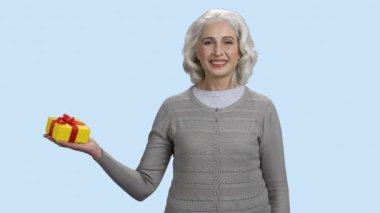 Gülümseyen olgun kadın avucunda hediye kutusu tutuyor..