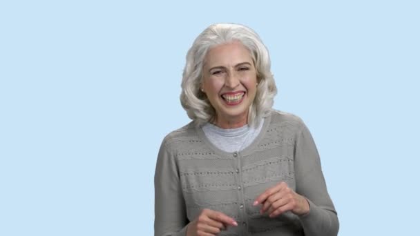 ผู้หญิงสูงอายุตลกหัวเราะบนพื้นหลังสีฟ้า — วีดีโอสต็อก