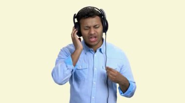 Neşeli Hintli adam kulaklıkla müzik dinliyor.