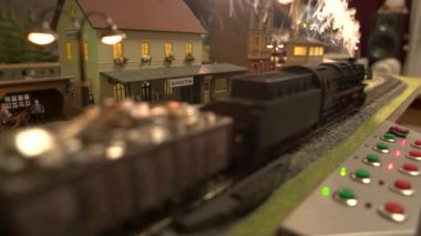 Tren istasyonundan buharlı bir model tren geçiyor..