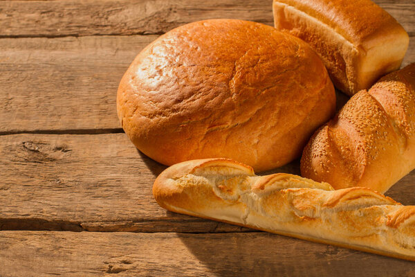 Assorted artisan bread on wooden background.