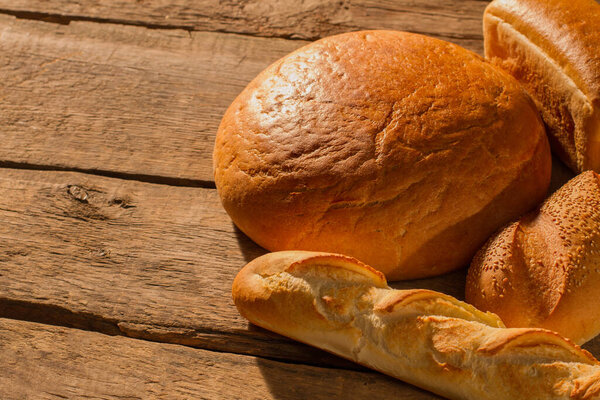 French bread and round bread on wooden background.