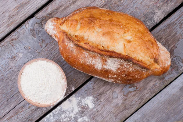 Świeży chleb rzemieślniczy i miska z mąką. — Zdjęcie stockowe