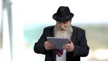 Neşeli son sınıf öğrencisi bilgisayar tabletinde oyun oynuyor.