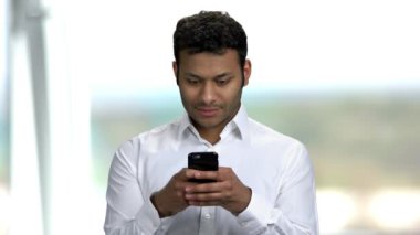 Hintli işadamı cep telefonuna mesaj yazıyor.