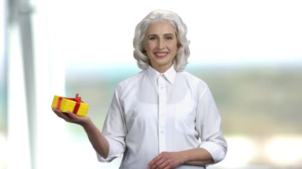 Glimlachende senior vrouw met geschenkdoos op haar handpalm. — Stockvideo