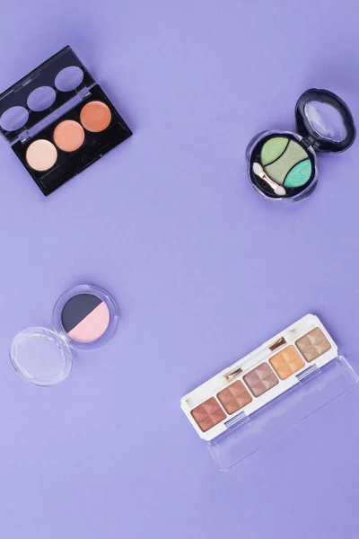 Polvos cosméticos variados sobre un fondo púrpura. — Foto de Stock