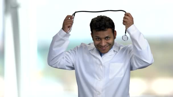 Молодой темнокожий доктор надевает стетоскоп. — стоковое видео