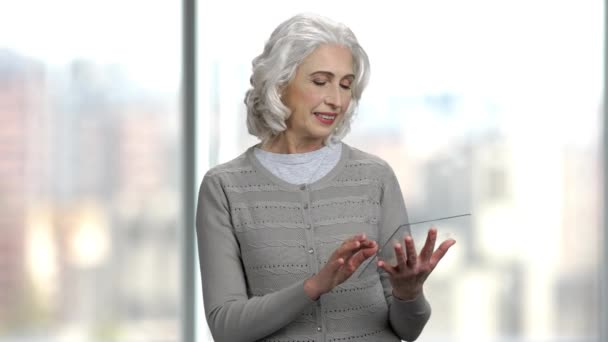 Donna matura utilizzando futuristico tablet trasparente. — Video Stock