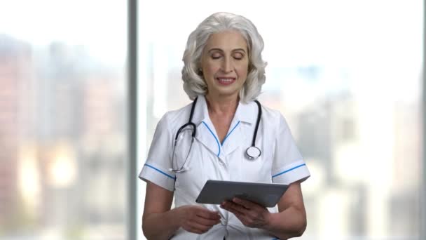 Mature female doctor holding computer tablet. — Stock Video