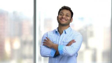 Genç gülümseyen adam bulanık arka planda kollarını kavuşturdu..